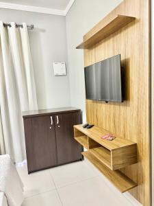 a living room with a flat screen tv on a wall at Quarto 2P Joinville Costa e Silva perto Centro in Joinville