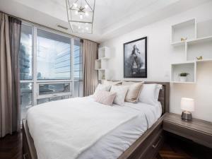 a bedroom with a large white bed with a window at Pristine Modern 2BR Condo Private BBQ and Balcony in Toronto