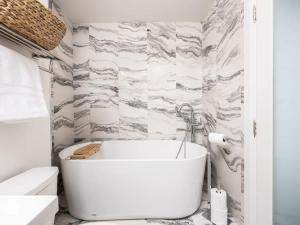 a white bath tub in a bathroom with marble walls at Pristine Modern 2BR Condo Private BBQ and Balcony in Toronto