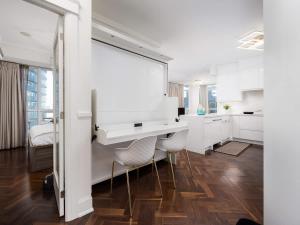 a white kitchen with a desk and two chairs at Pristine Modern 2BR Condo Private BBQ and Balcony in Toronto