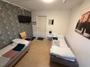 a room with two beds and a wall with a tv at Bakgården Mariestad in Mariestad