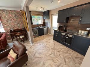 a kitchen with black cabinets and a living room at Cerrig in Llangollen