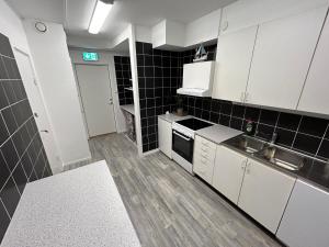 a small kitchen with white cabinets and black tiles at Bakgården Mariestad in Mariestad
