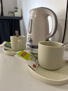 a tea kettle and two cups on a counter at Monoambiente B en Corrientes Capital in Corrientes