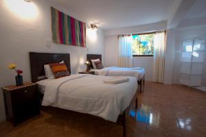 a hotel room with two beds and a window at Piedra Wasi Ecolodge Urubamba in Urubamba