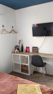 a desk with a chair and a television on a wall at Entre Bois & Cévennes in Anduze