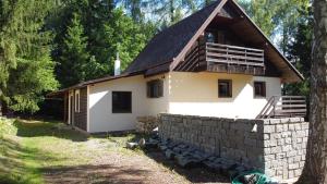 a small white house with a brick wall at Na samotě u lesa in Libňatov