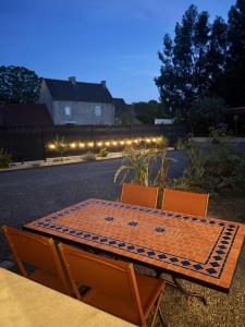 a table and two chairs with a table and lights at Maison détente in Nonant