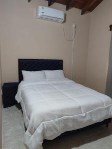 a bedroom with a white bed with a black headboard at Casa con dos Dormitorios in Encarnación +2 photos