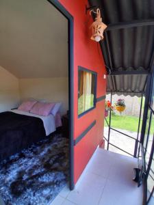 a bedroom with a bed and a red wall at Hospedaje Maria Valentina in Tota