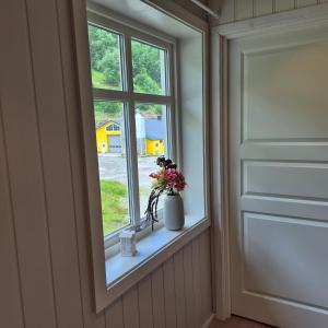 a window with a vase of flowers on a window sill at Molden Sky - takterrasse med egen jacuzzi! in Luster