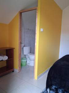 a bathroom with a toilet and a yellow wall at Hospedaje Maria Valentina in Tota +42 photos