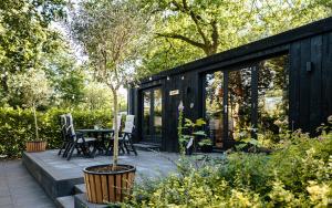 a black shed with a table and chairs in a garden at Meikever in Putten