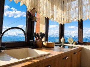 a kitchen with a sink and large windows at Datvina Panorama Chalets Mravaldzali, Racha in Oni