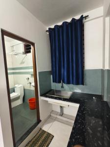 a bathroom with a sink and a blue shower curtain at K K Residency in Alwaye