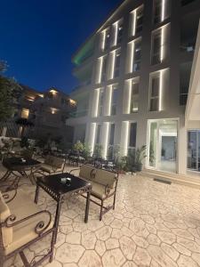 a patio with tables and chairs in front of a building at Hotel Noel in Vlorë
