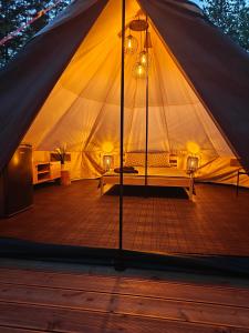 a tent with a wooden deck with a bed in it at AVOTUPJI GLEMPING telts in Allaži