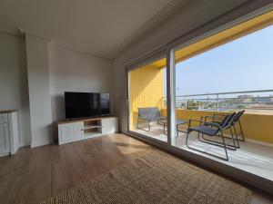 a living room with a balcony with a television and chairs at Playa Los Náufragos Torrevieja in Torrevieja