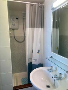 a bathroom with a sink and a shower with a shower curtain at Downshire House in Douglas