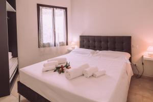 a large white bed with white towels and flowers on it at Appartamenti I Lentischi in Villasimius +37 photos