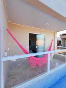 een balkon met een roze hangmat erop bij Costa Suítes in Maragogi
