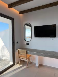 a living room with a tv and a chair at Salt and stone suites in Vrachonisída touArchangélou