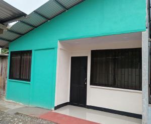 a green and white building with a black door at Señora Aura in Hone Creek