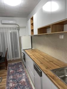 a kitchen with white cabinets and a wooden counter top at Bleon Apartment in Prizren