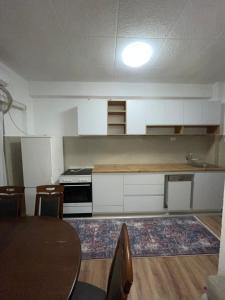 a kitchen with white cabinets and a table with chairs at Bleon Apartment in Prizren +4 photos