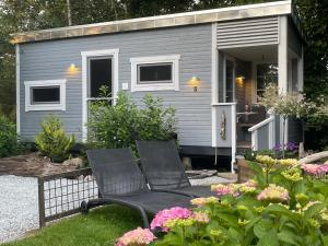 a tiny house with two chairs in a garden at Lille Degnboel Tiny House in Hjørring