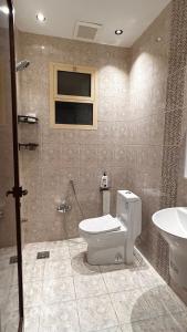 a bathroom with a toilet and a sink at شالية بمسبح وجلسة خارجية- غرفتين نوم وملحق خارجي ومدخل سيارة in Unayzah +5 photos