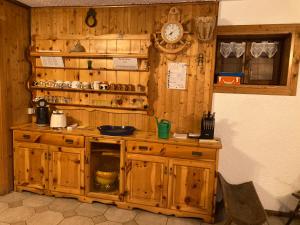 a kitchen with wooden cabinets and a clock on the wall at Baita Palue in Torcegno