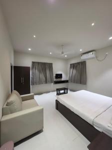 a bedroom with a large bed and a couch at NilayInn in Pandharpur