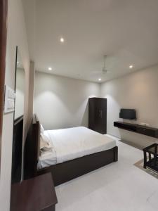 a white bedroom with a bed and a desk at NilayInn in Pandharpur