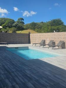 a swimming pool with two lounge chairs next to a brick wall at VILLA Orchidée in Le Moule +1 photo