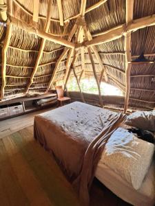 a bed in a thatched room with a window at Casa Alma in Sayulita