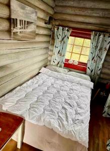 a bed in a log cabin with a window at Grasbakken hytteutleie in Nesseby
