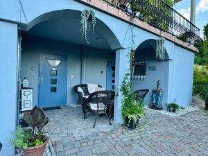 a patio with two chairs and a blue house at Vila Kralj in Podčetrtek