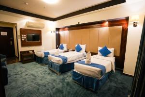 a hotel room with three beds and a television at فندق برج السيف in Mecca