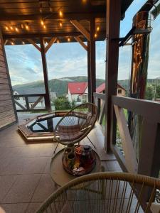 a rocking chair on a balcony with a view of the mountains at Карпатська Вершина in Yaremche