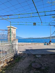 a person sitting on a bench near the water at Sanrise Hostel in Baošići