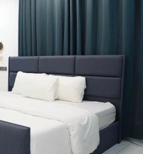ein Bett mit blauem Kopfteil und weißen Kissen in der Unterkunft Cross Suites in Tema + 5 Fotos