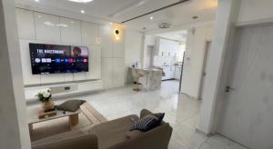 ein Wohnzimmer mit einer Couch und einem Fernseher an der Wand in der Unterkunft Cross Suites in Tema