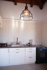 a kitchen with white cabinets and a sink and a lamp at Pinat HaNahal in HaGoshrim +9 photos