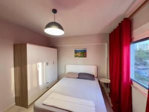 a small bedroom with a white bed and a window at Luna Apartment in Durrës