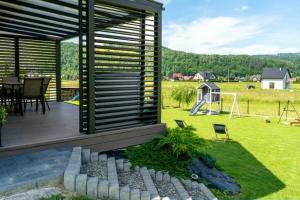a house with a deck and a playground at Domek pod Nowiną in Tylmanowa