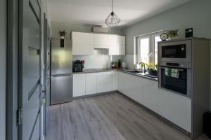 a kitchen with white cabinets and stainless steel appliances at Domek pod Nowiną in Tylmanowa