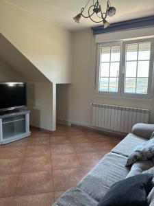 a living room with a couch and a flat screen tv at Casa Mar de Neaño in Neaño