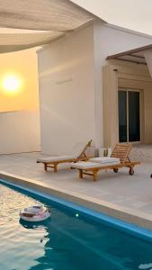 a pool with two benches next to a house at In The Peaks in Sharīyah +23 photos