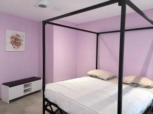 a bedroom with a four poster bed and purple walls at Mais Residence in Bijilo +38 photos